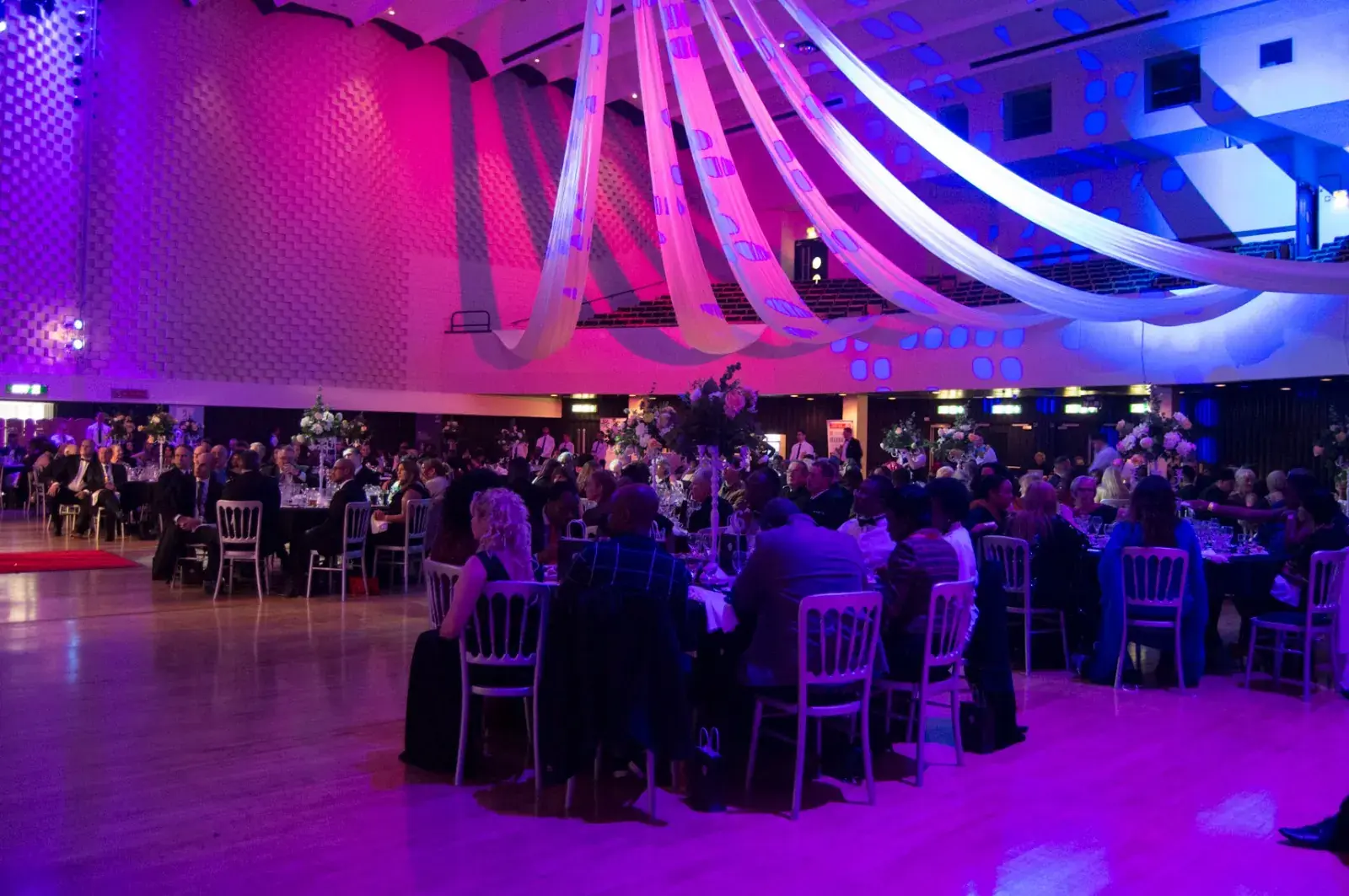 The ballroom at Lighthouse, Poole, full of guests at dinner tables under draped ceiling lights