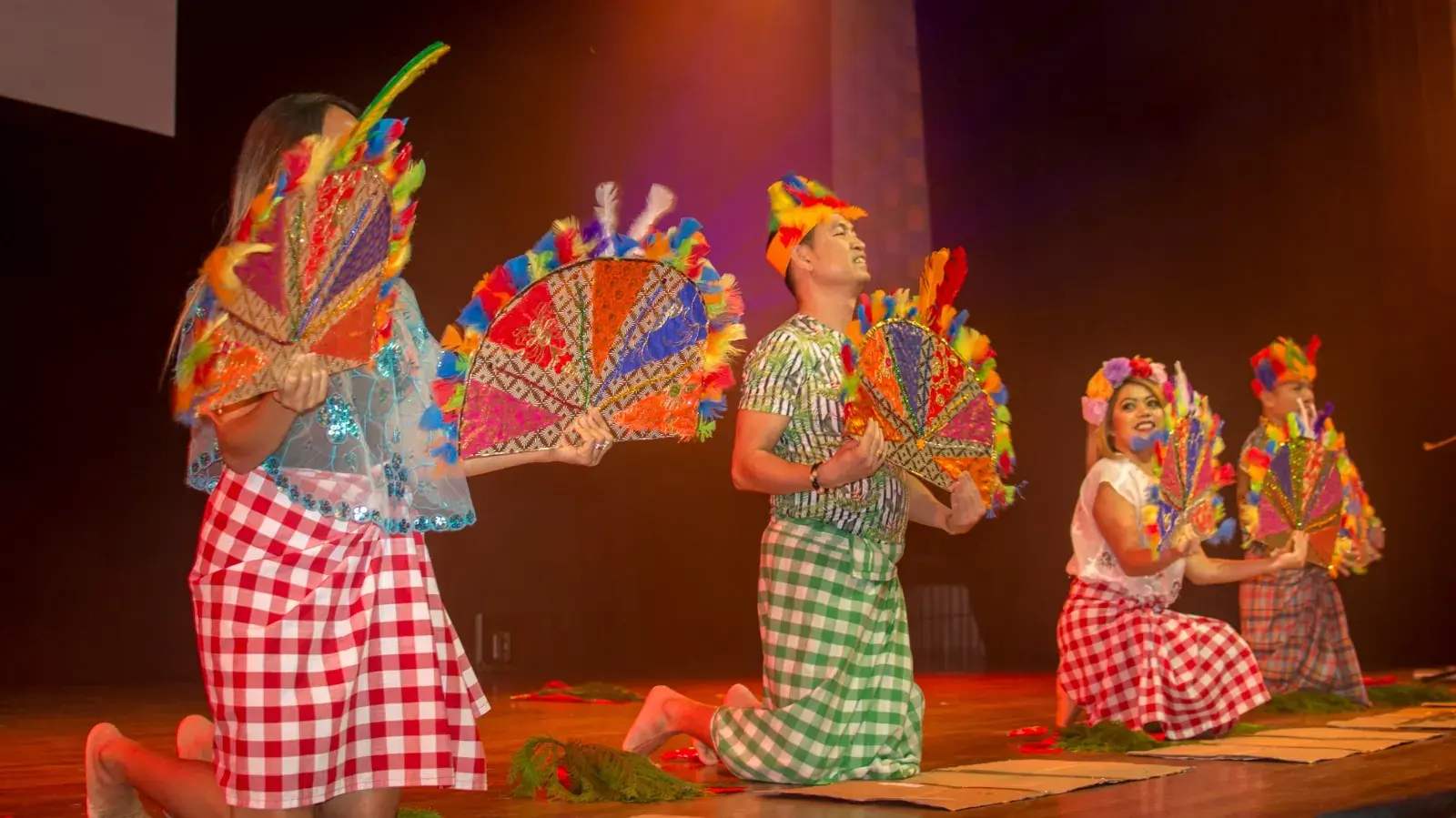 Dancers performing with colourful feathered fans on stage